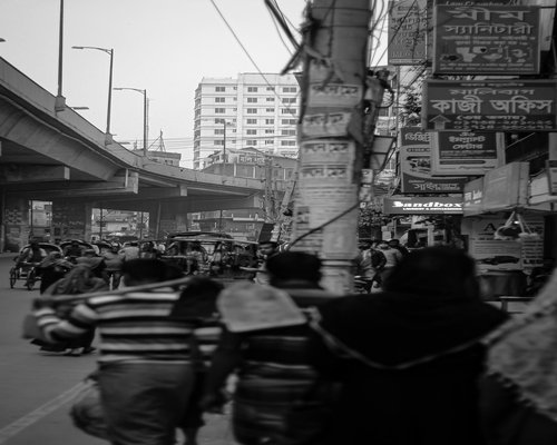 People walking on a sidewalk in a busy Bangladeshi city